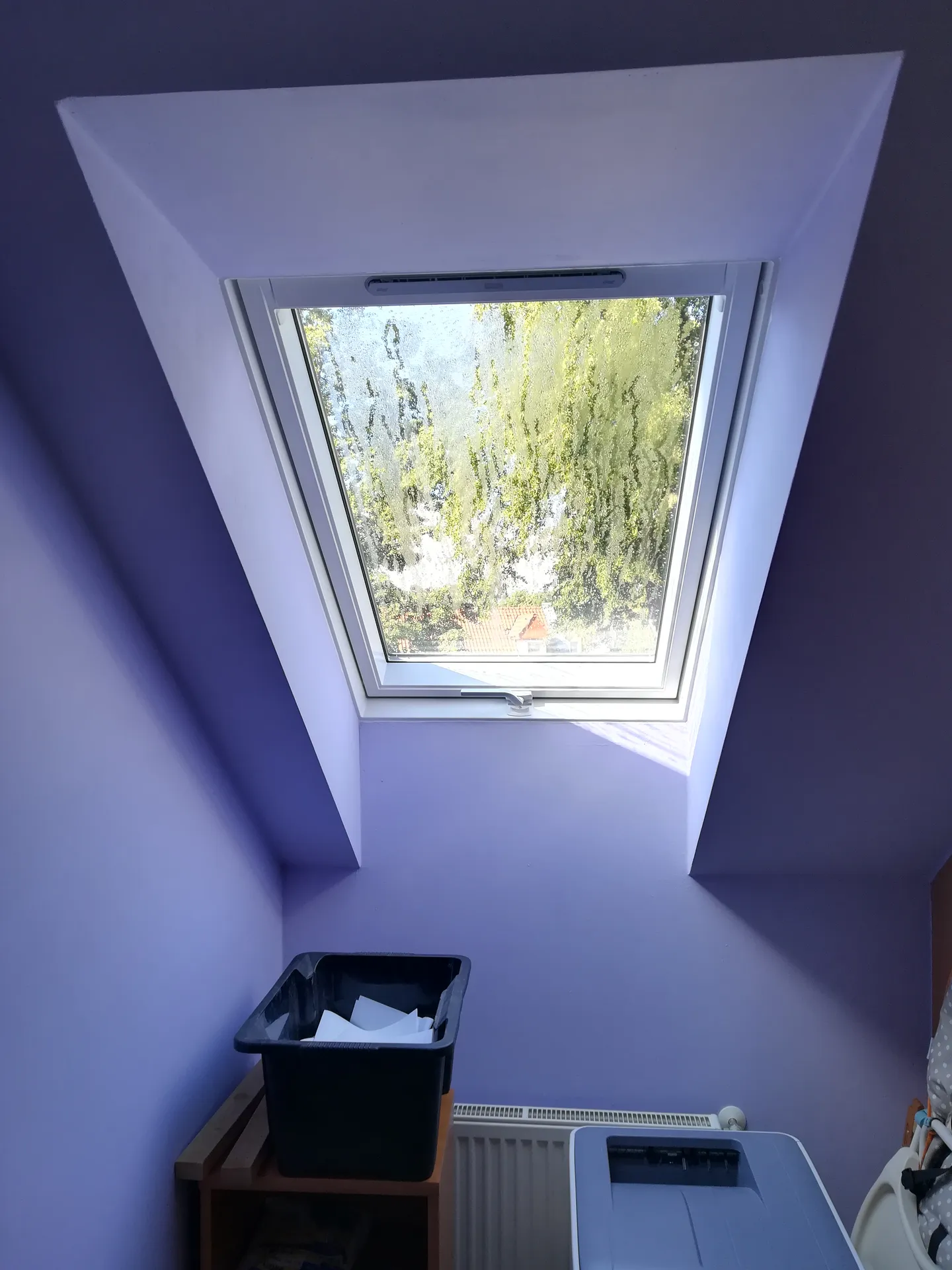 Střešní okno ve fialovém pokoji nad radiátorem